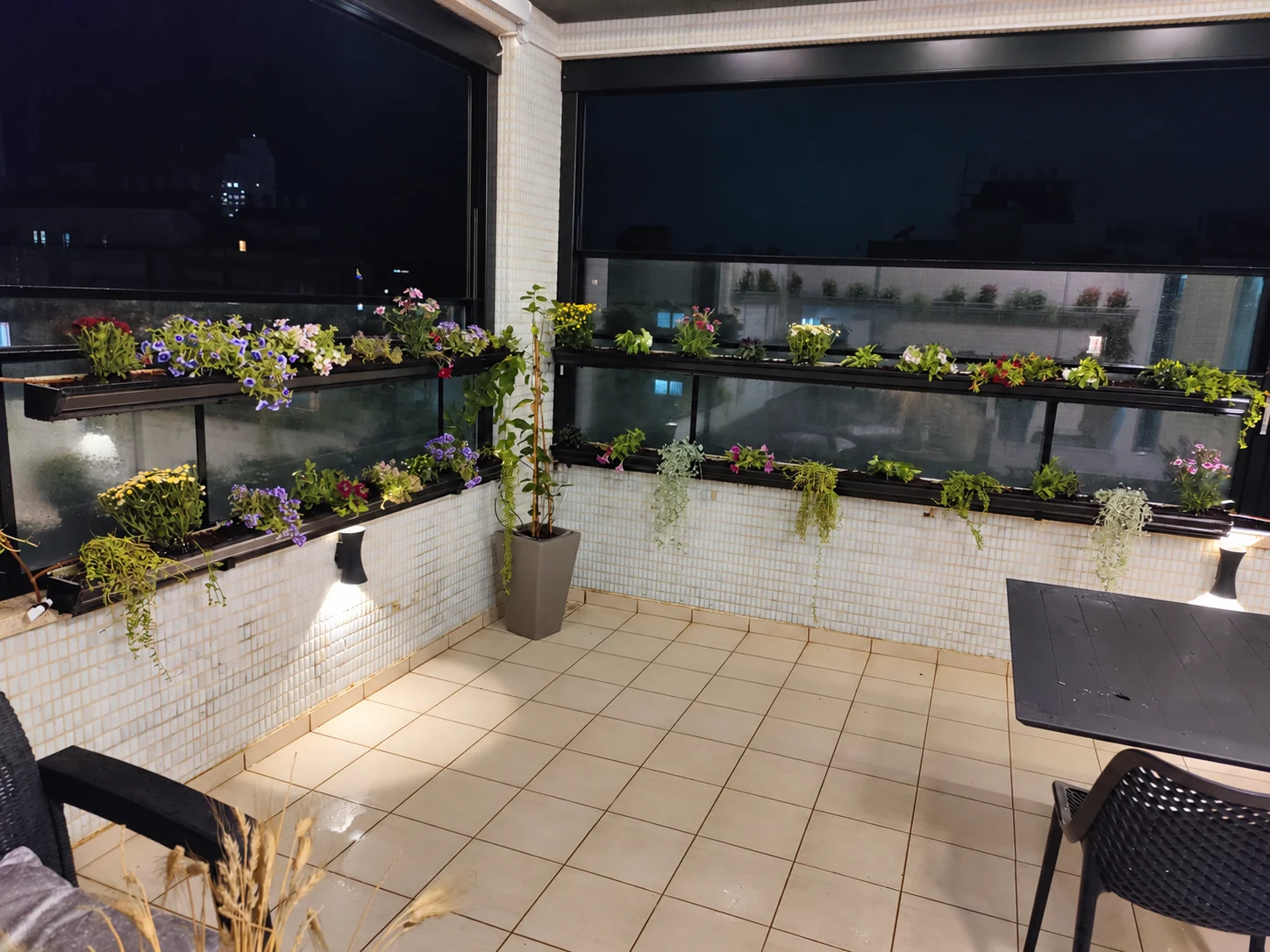 אדניות לאורך קירות המרפסת ומעקה החלונות, בצילום ערב.